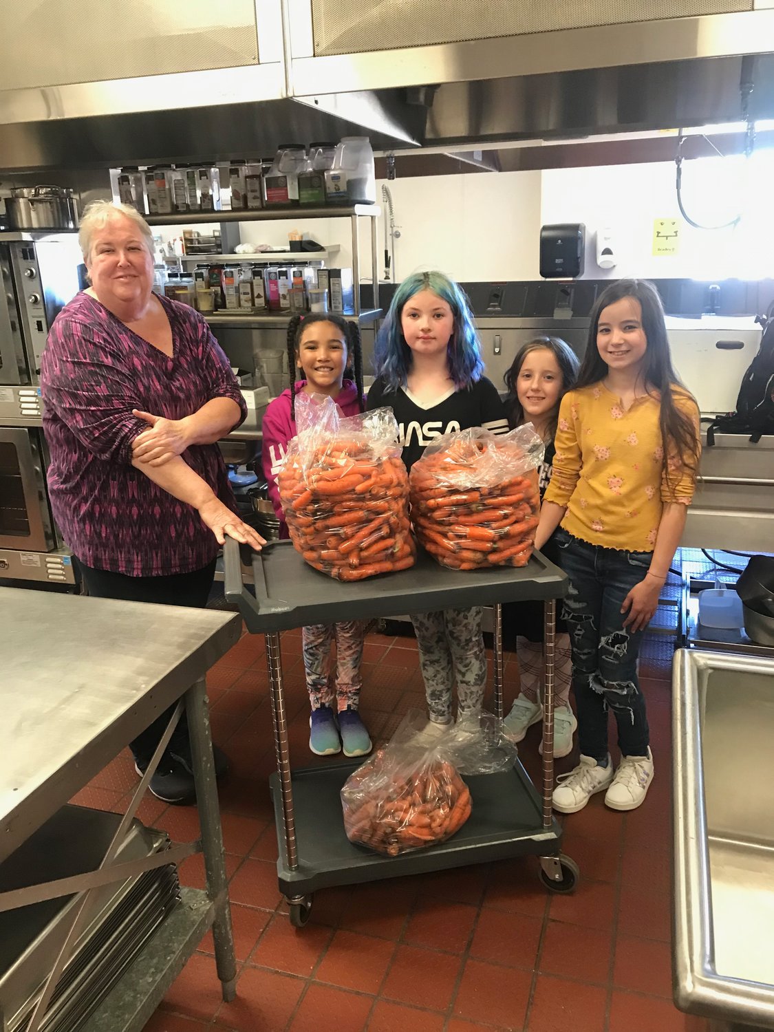 Carrot Delivery: Fourth-graders from Chimacum Elementary deliver a load of school-grown carrots to Food Service Director Margaret Garrett for use in school meals. Photo courtesy of Chimacum Elementary School.